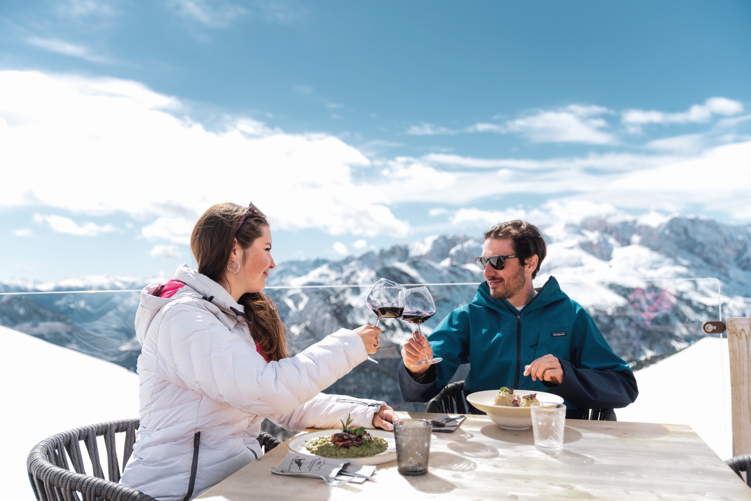 Couple eating meal with snow scene background, Val di Fassa