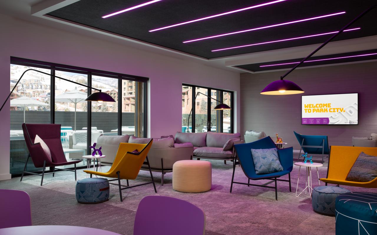 Contemporary tables, chairs, décor, and lighting in the Yotelpad lounge with views of the pool and mountain village