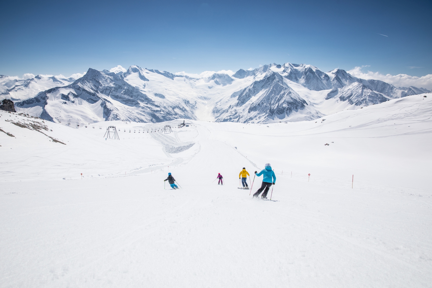 Family skiing down piste with mountains in background - Zillertal, Austria