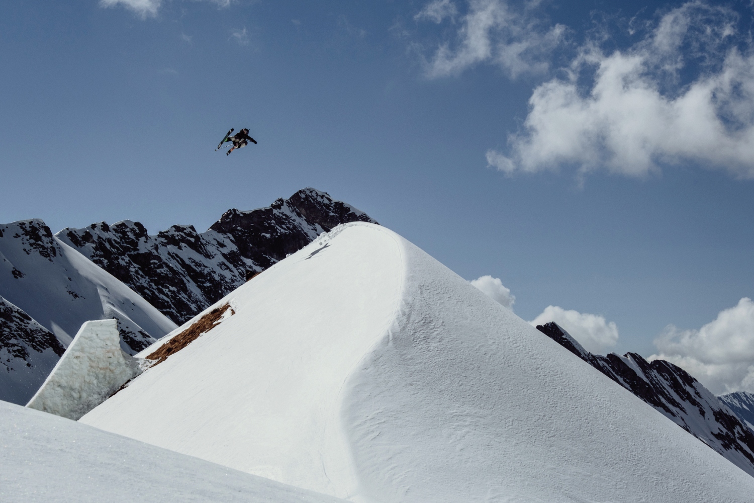 Skier jumping mid-air from mound of snow