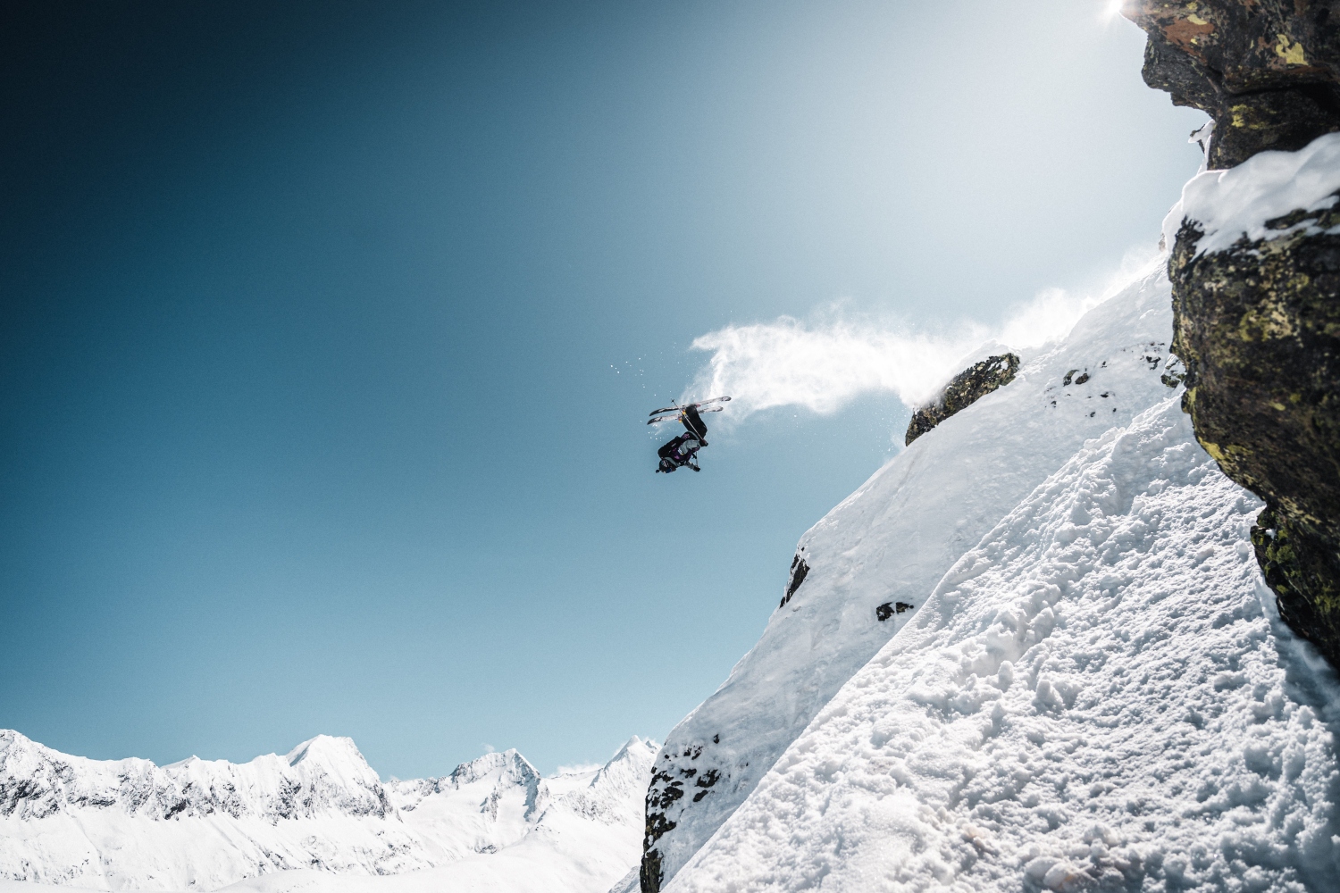 Skier jumping off snowy rock