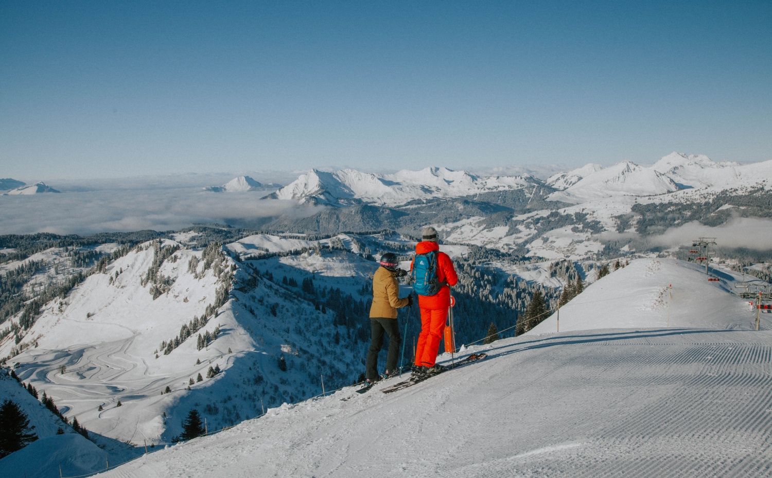 Skiers at top of slope looking out over mountains