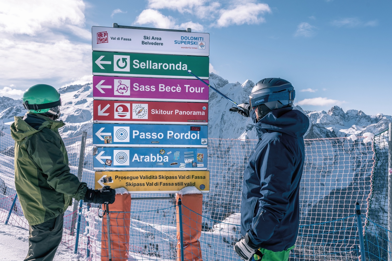 Skiers looking at sign for Ski Area Belvedere, Val di Fassa