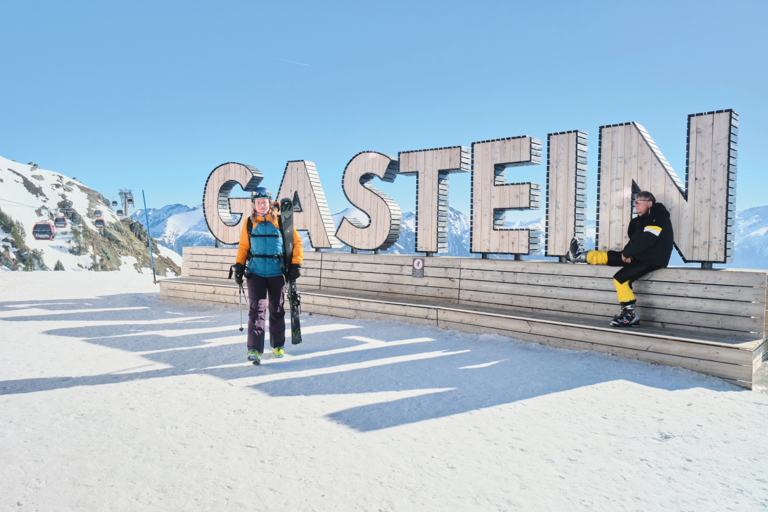 Skiers next to Gastein sign