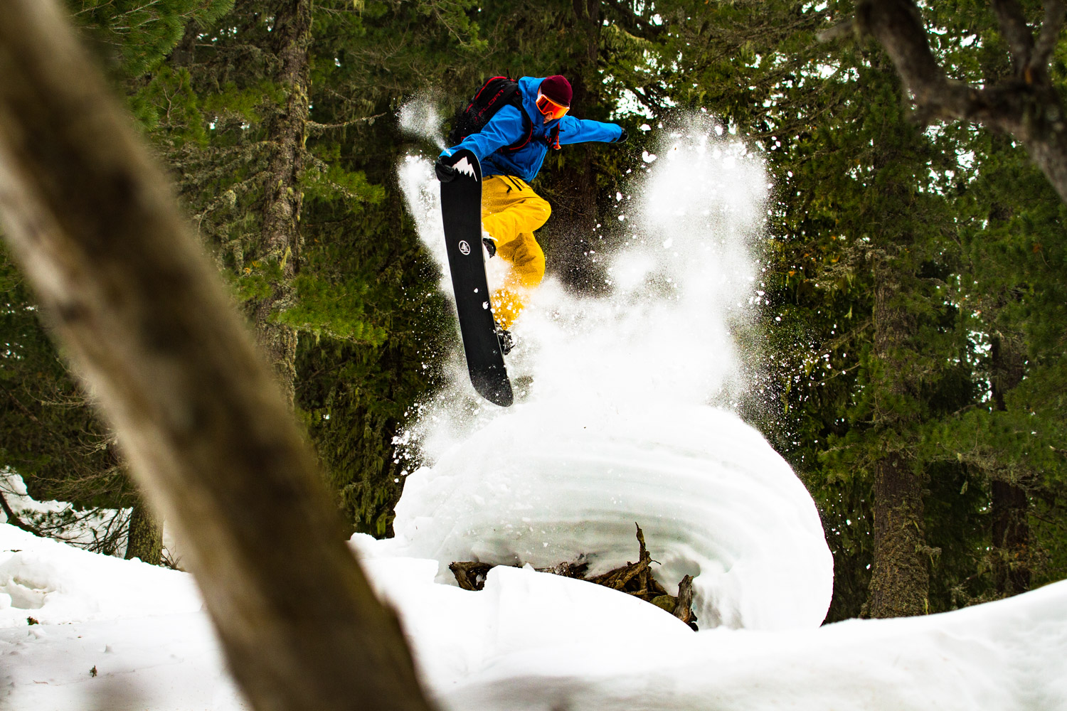 Snowboarder jumping from snow pile