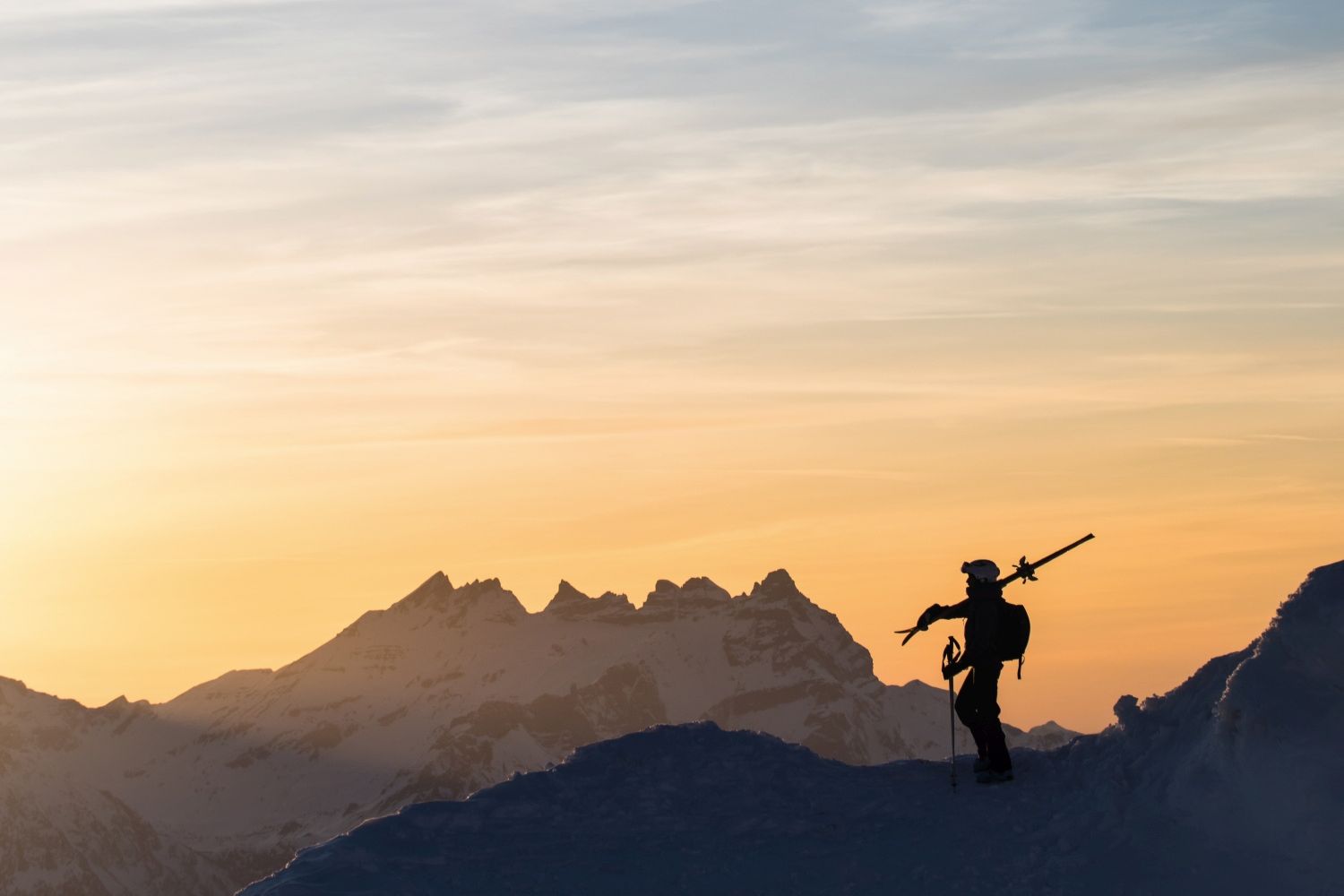 Skier looking over mountains on a sunset ski tour