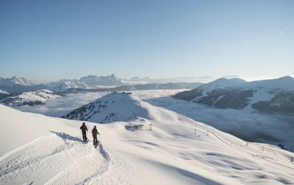 Skiers looking out across snowing mountainscape Skicircus Freeride CREDIT Skicircus Saalbach Hinterglemm Leogang Fieberbrunn
