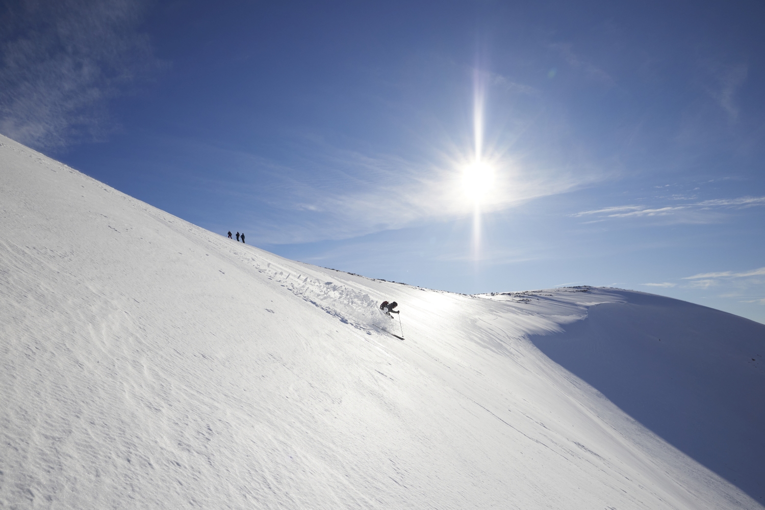 Skier creating snow dusting riding down fresh slope, Scotland