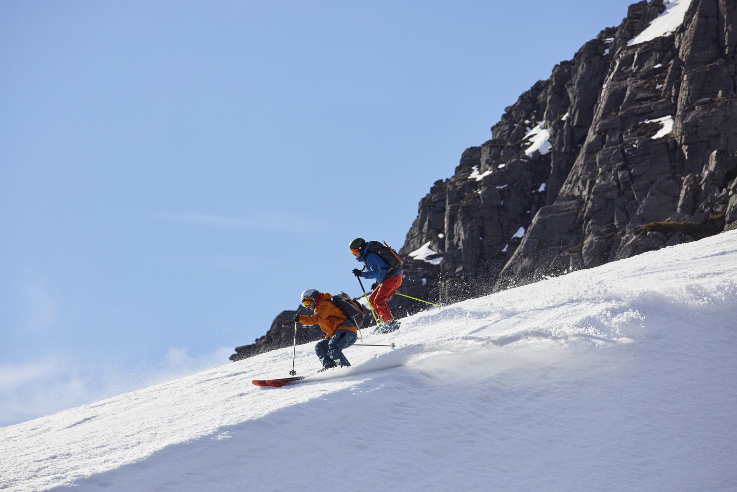Two people skiing with blue sky background, Scotland