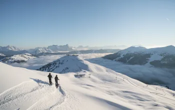 Skiers looking out across snowing mountainscape Skicircus Freeride CREDIT Skicircus Saalbach Hinterglemm Leogang Fieberbrunn