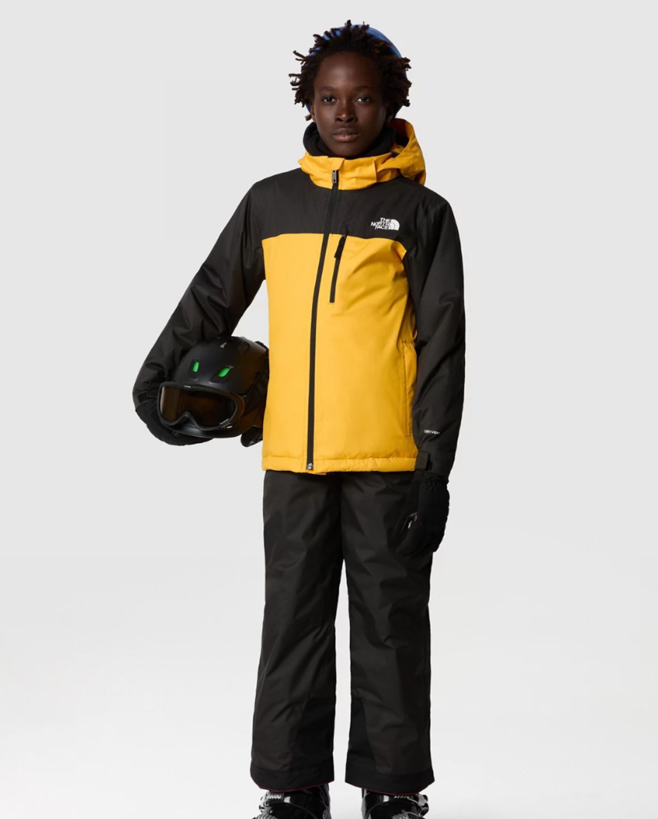 Teenage boy in yellow and black jacket holding a helmet_North Face